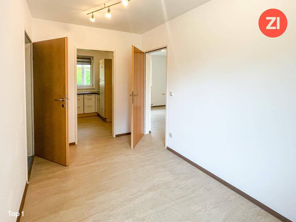 Flur- oder Eingangsbereich mit hellem Laminatboden und Blick in eine angrenzende Küche.
