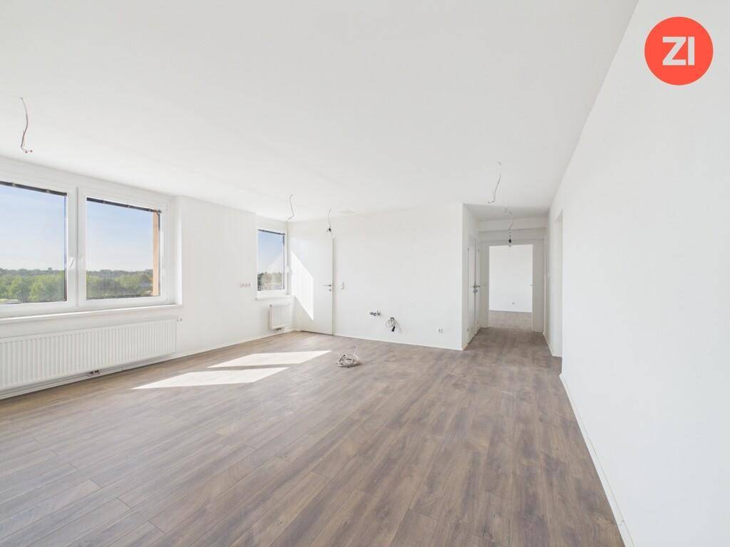 Lichtdurchfluteter Wohnbereich mit Laminatboden, weißen Wänden und Blick in den Flur.