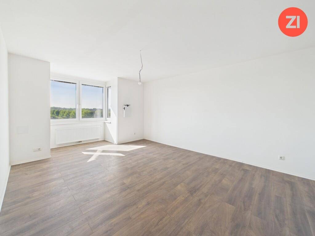 Heller und geräumiger Wohnraum mit großen Fenstern und einem angenehmen Blick ins Grüne.