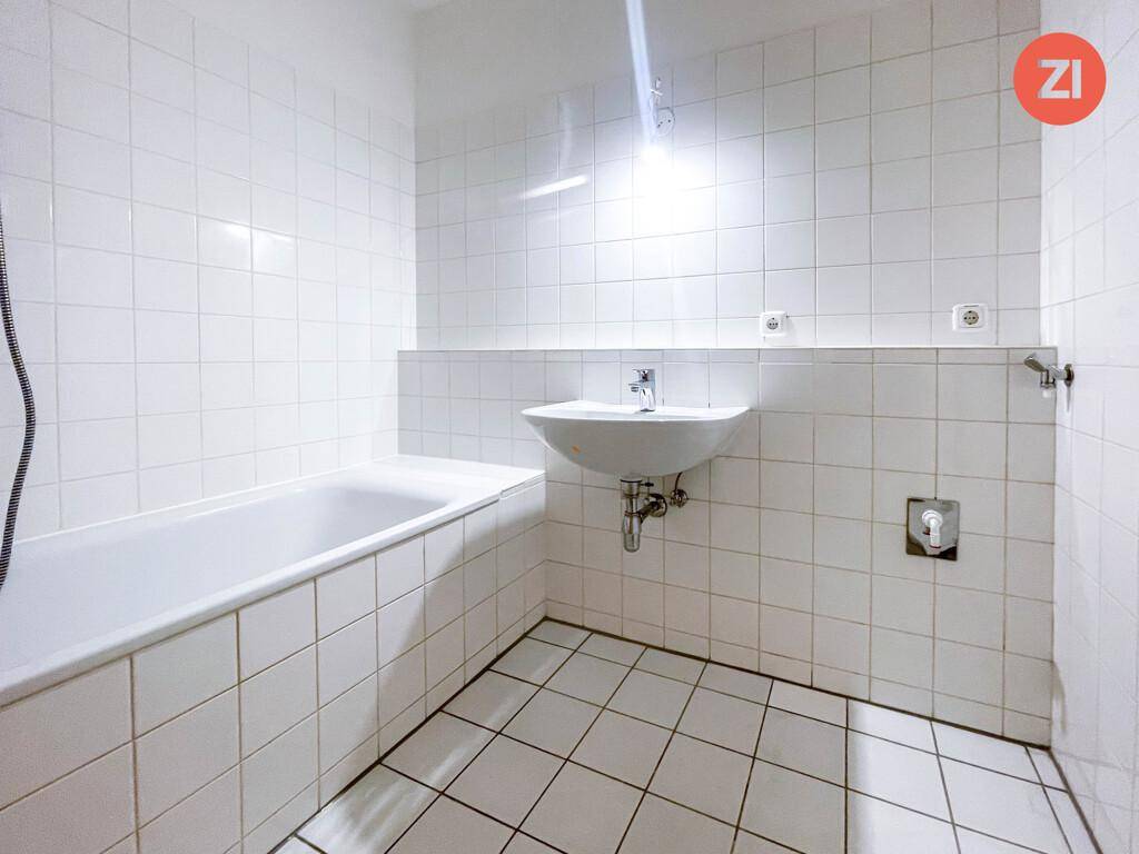 Gefliestes Badezimmer mit Badewanne und Waschbecken in gutem Zustand.