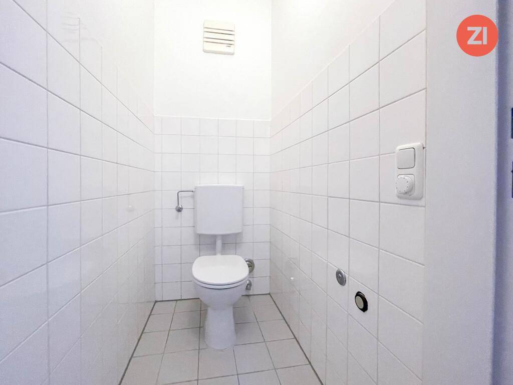 Sauber gefliestes separates WC mit Toilette und Lüftung.