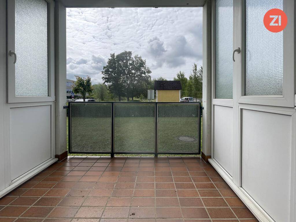 Kleiner Balkon mit Fliesenboden und Blick ins Grüne.