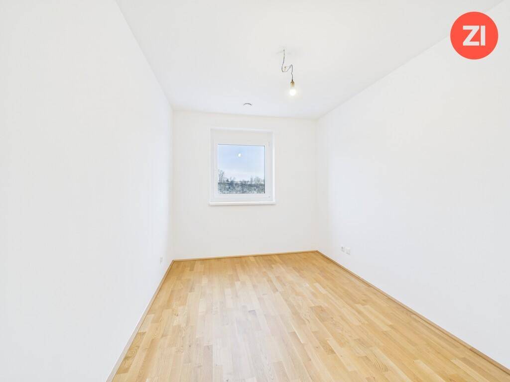 Geräumiges Schlafzimmer mit hellem Parkettboden und einem Fenster für natürliche Belichtung.