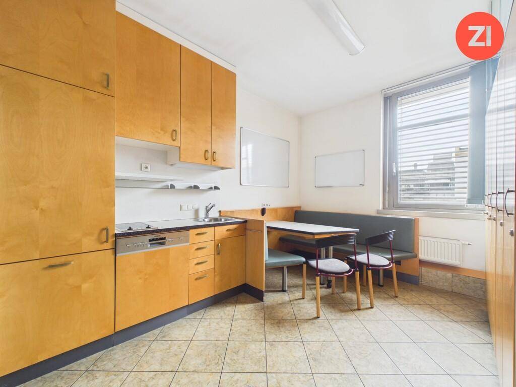 Funktionale Einbauküche mit Holzschränken, Spülmaschine und Essbereich, ideal für Pausen.