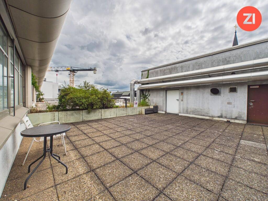 Geräumige Dachterrasse mit Pflastersteinen, Sitzgelegenheiten und Blick auf die Umgebung.