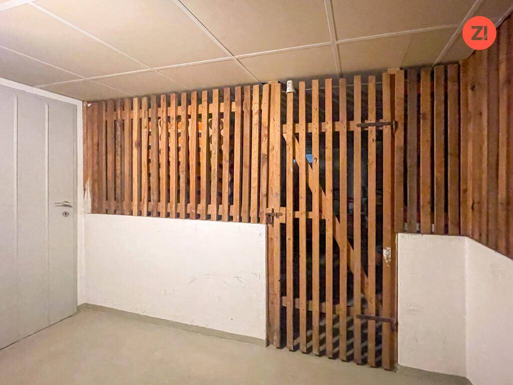 Kellerabteil mit Holzlattenwänden und Betonboden, ideal für zusätzlichen Stauraum.