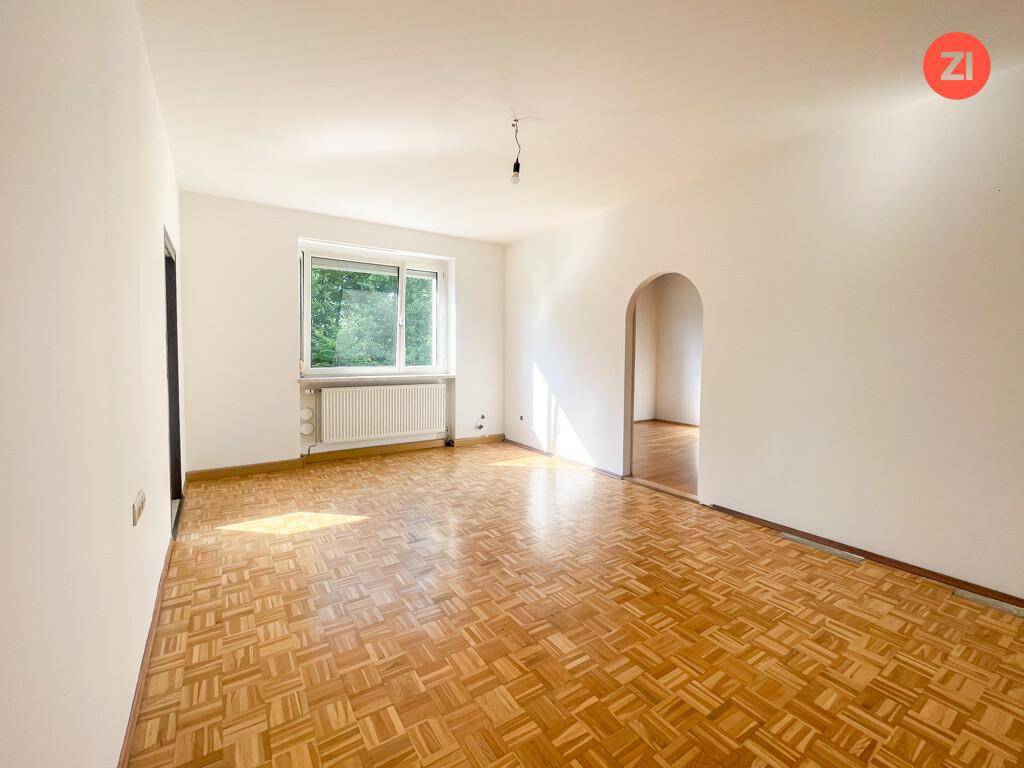 Heller Wohnraum mit Parkettboden, weißen Wänden und viel Tageslicht durch das Fenster.