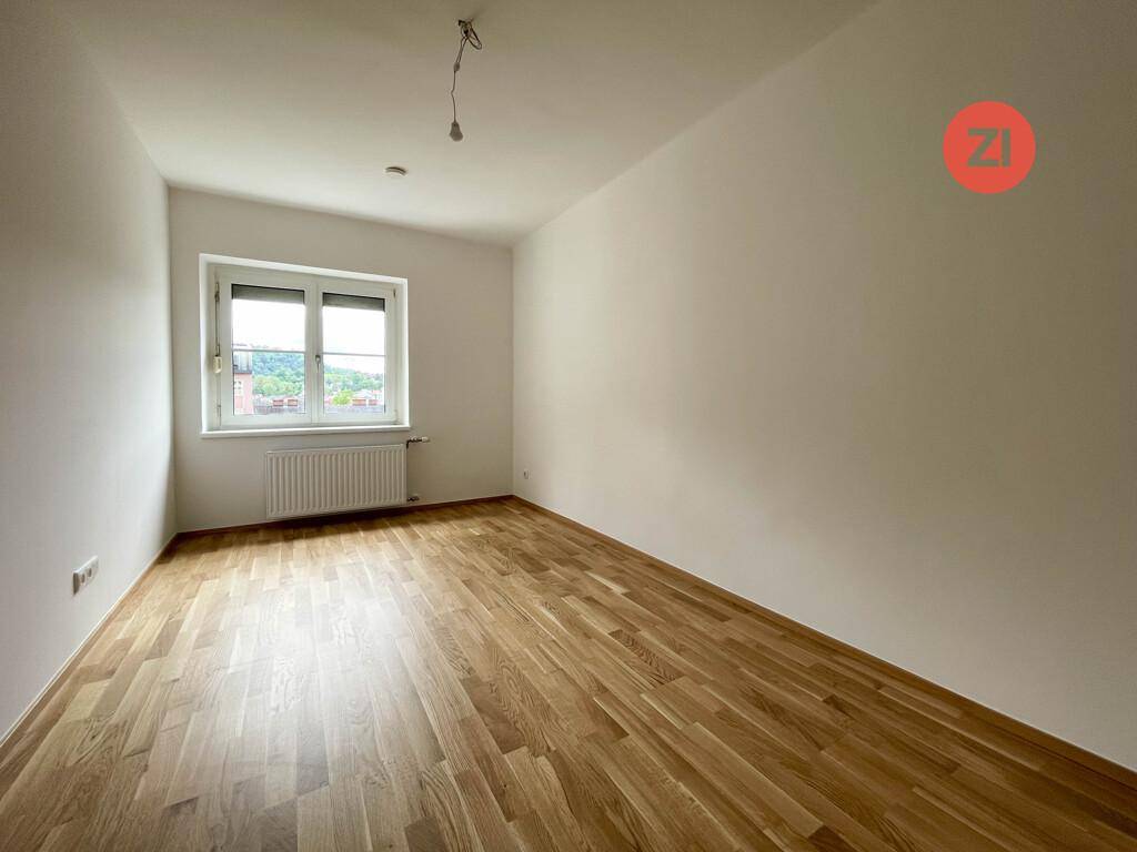 Geräumiges, leeres Zimmer mit hellem Parkettboden und einem Fenster, ideal als Schlaf- oder Arbeitszimmer.