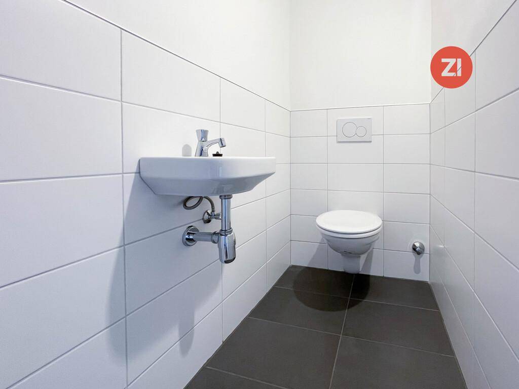 Kleines, hell gefliestes Gäste-WC mit wandhängender Toilette und modernem Waschbecken.
