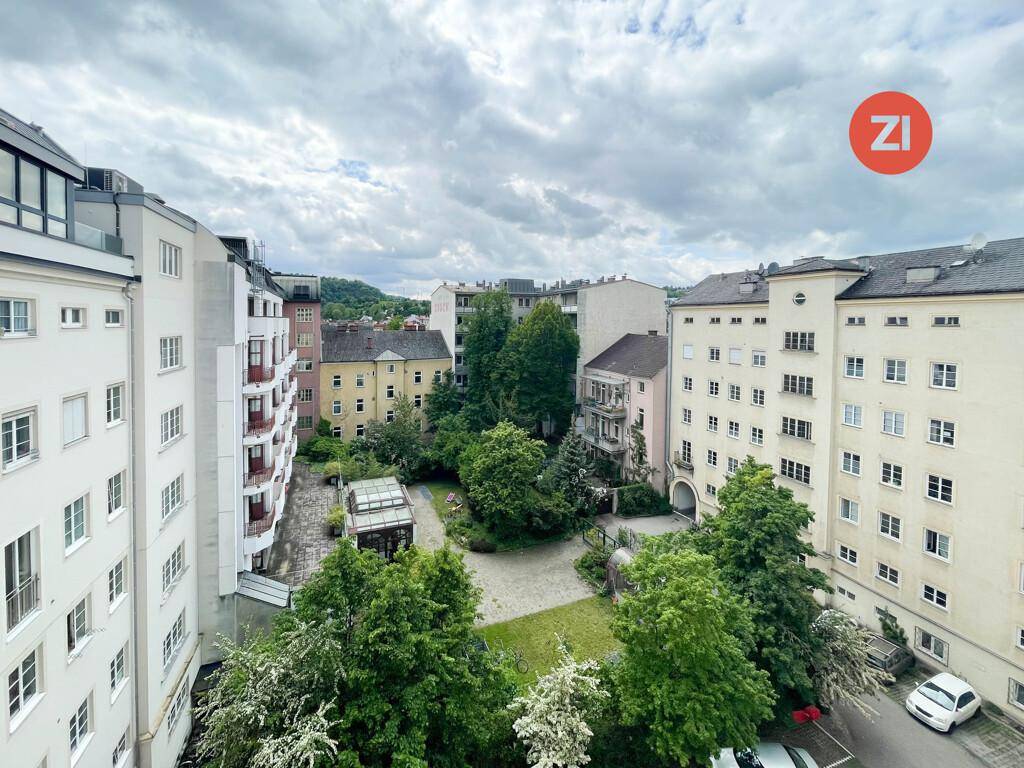 Blick von oben auf einen grünen Innenhof, umgeben von Wohngebäuden mit Bäumen und Wegen.