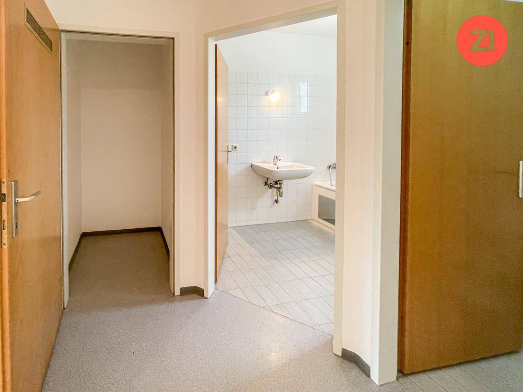 Flur mit Zugang zu einem Badezimmer und einem weiteren Raum, ausgestattet mit Holztüren.