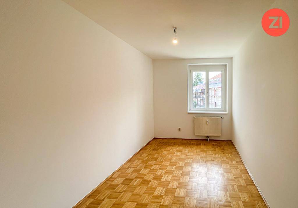 Geräumiges Schlafzimmer mit Parkettboden und einem Fenster, das den Raum erhellt.
