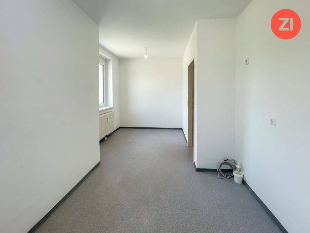 Leerer Raum mit grauem Boden und weiß gestrichenen Wänden, bereit zur Gestaltung.