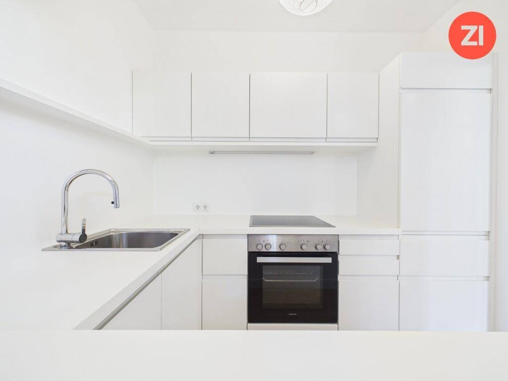 Moderne, weiße Einbauküche mit Induktionskochfeld, Backofen und integrierter Spüle.