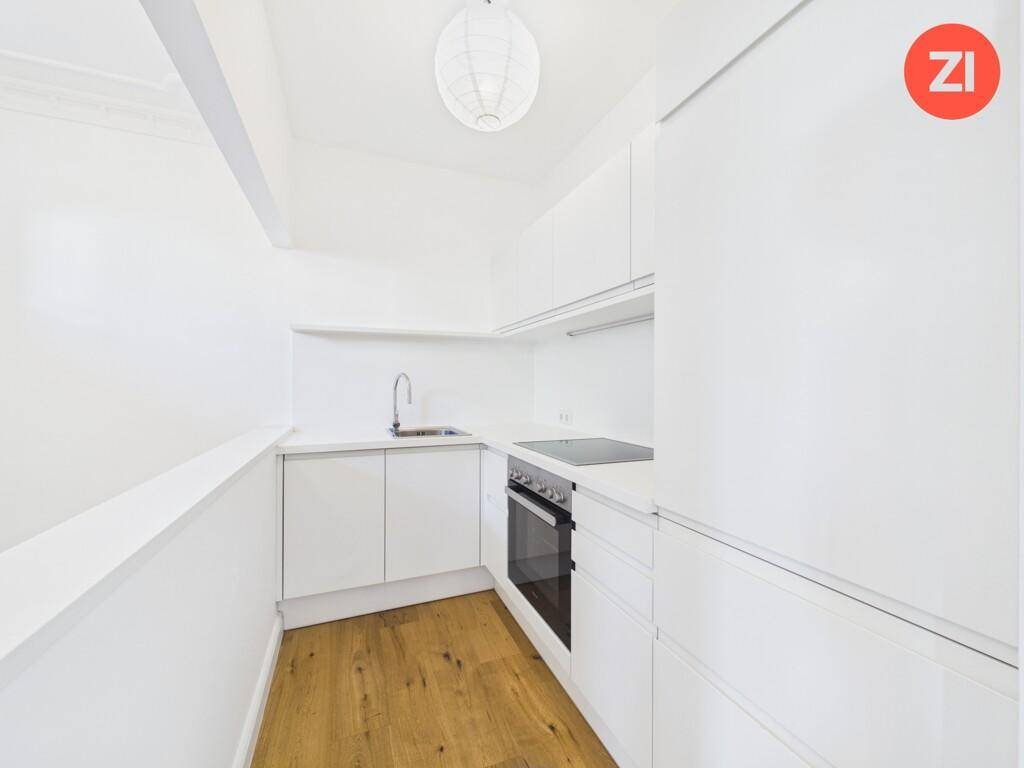 Kompakte, moderne Küche in Weiß mit Holzboden und effizienter Raumausnutzung.