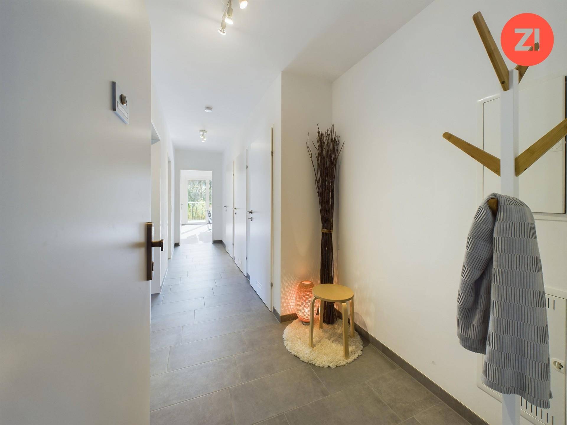 Heller Flur mit modernen Fliesen, Garderobe und Zugang zu weiteren Räumen.