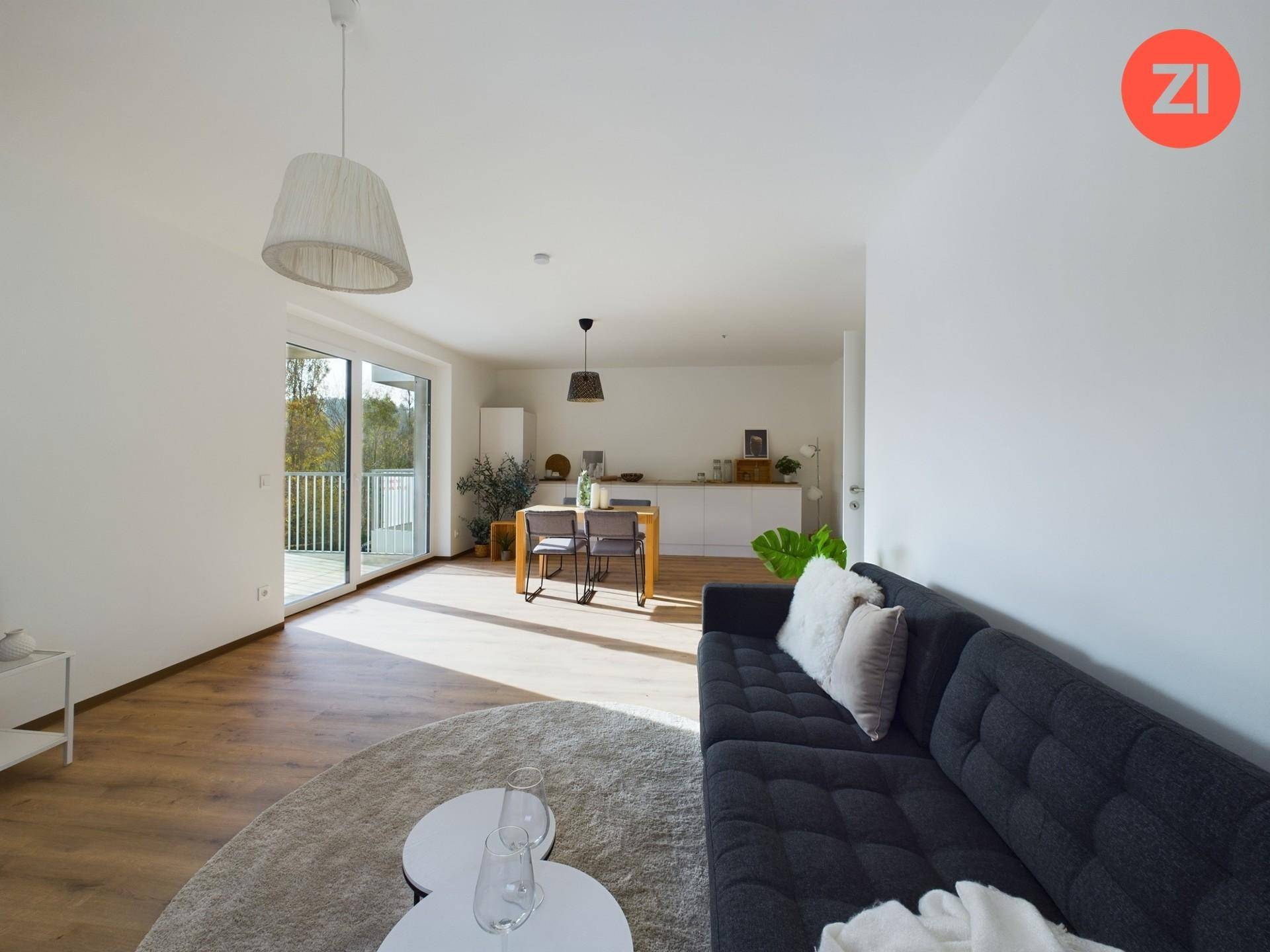 Heller Wohn-Essbereich mit Sofa, Esstisch und Zugang zu einem sonnigen Balkon.