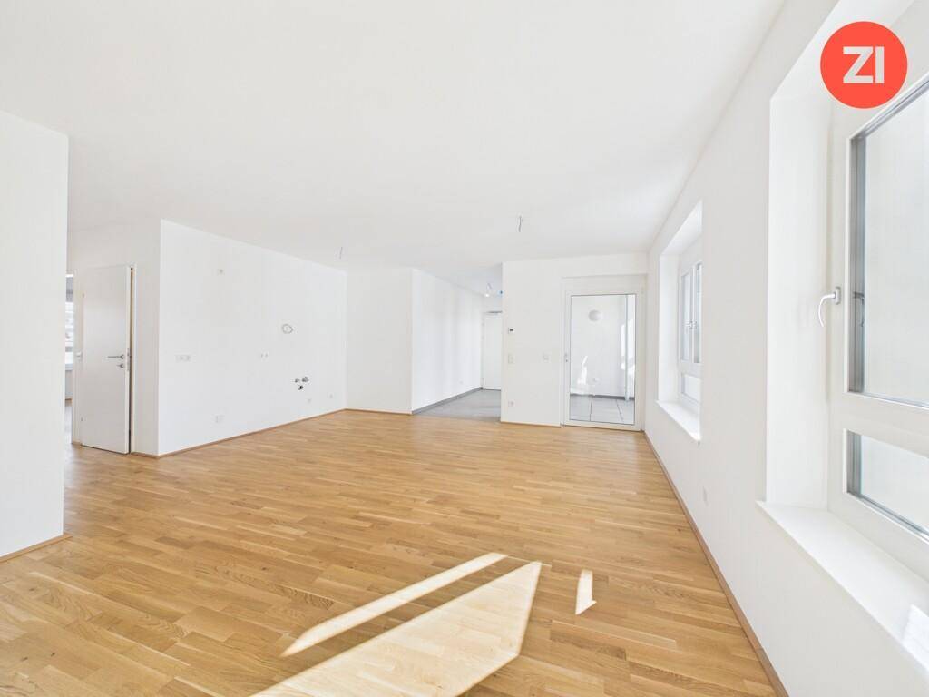 Heller Wohnraum mit Parkettboden und Fenstern, die viel Tageslicht hereinlassen.