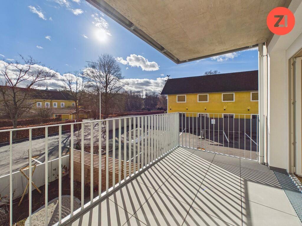 Sonniger Balkon mit grauen Fliesen und weißem Geländer, bietet einen Blick auf die Umgebung.