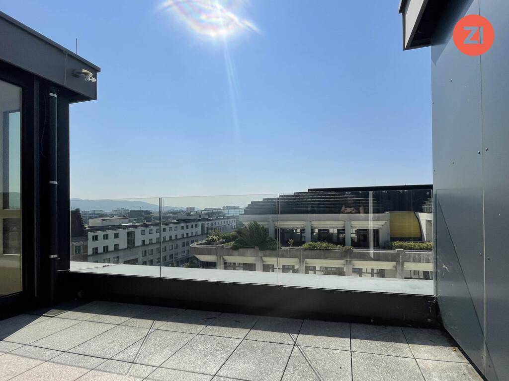Sonniger Außenbereich mit Glasgeländer und weitem Blick über die Stadt und die Landschaft.