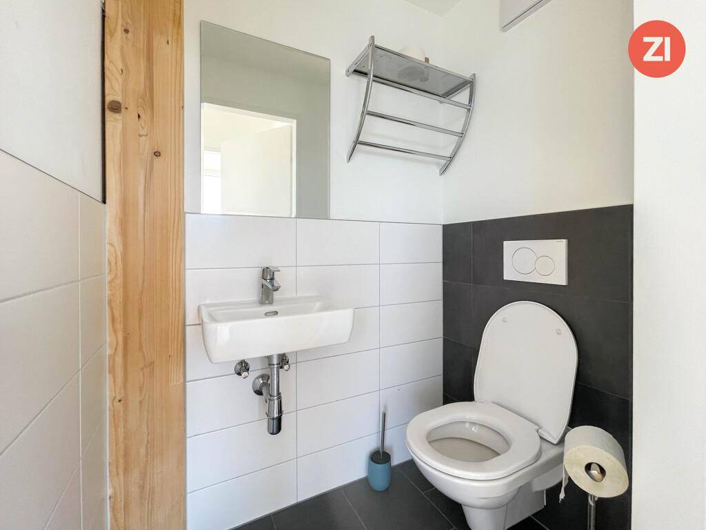 Gäste-WC mit Wand- und Bodenfliesen, Toilette und kleinem Waschbecken.