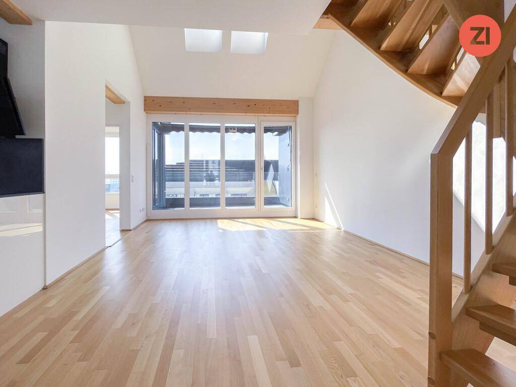 Lichtdurchfluteter Wohnbereich mit großen Fenstern, Zugang zum Balkon und Dachfenstern.