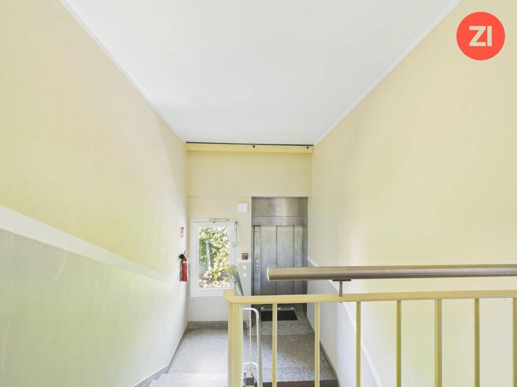 Helles Treppenhaus mit Aufzug und Fenster, das den Zugang zu den Etagen erleichtert.