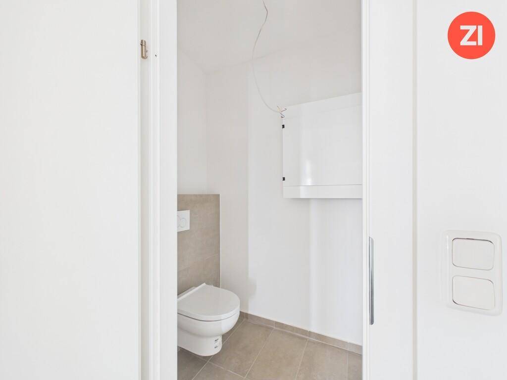 Modernes Gäste-WC mit Wand-WC und hellen Fliesen, funktional und sauber.