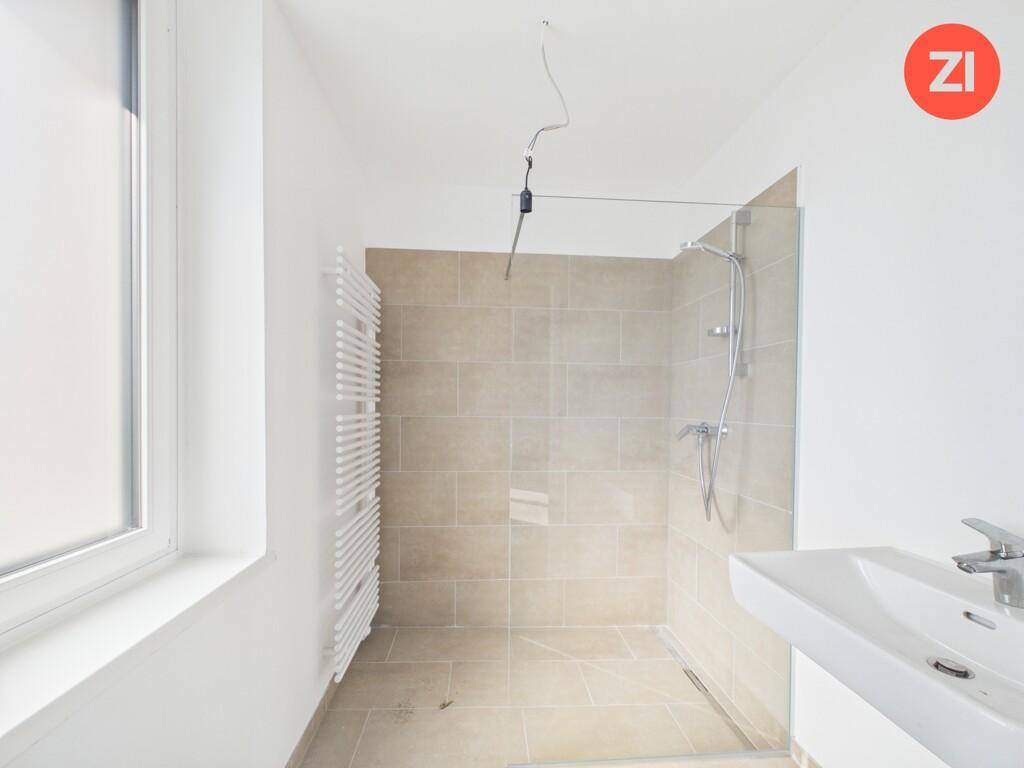 Modernes Badezimmer mit begehbarer Dusche, Waschbecken, beheiztem Handtuchhalter und Fenster.