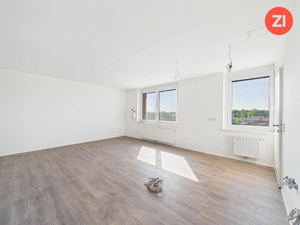 Geräumiges, helles Zimmer mit Laminatboden und mehreren Fenstern, ideal für individuelle Gestaltung.