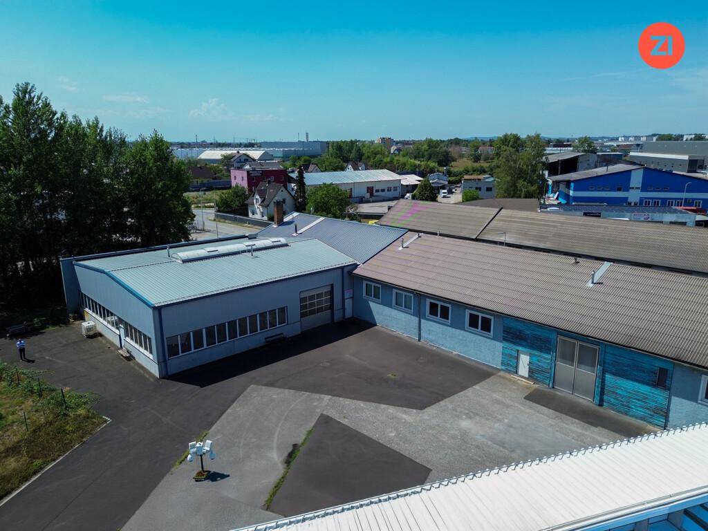 Blick von oben auf ein Gewerbeareal mit mehreren Hallen und einem großen, gepflasterten Vorplatz.