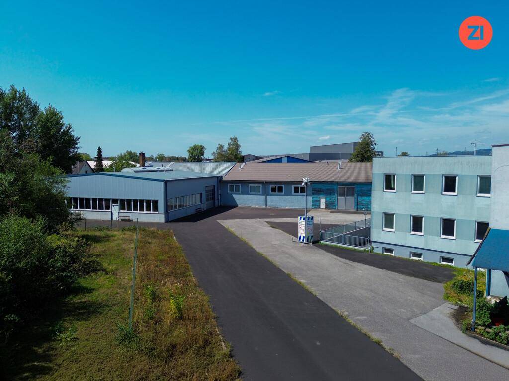 Gewerbegebäude mit asphaltierter Zufahrt und Grünflächen, umgeben von weiteren Industrieanlagen.