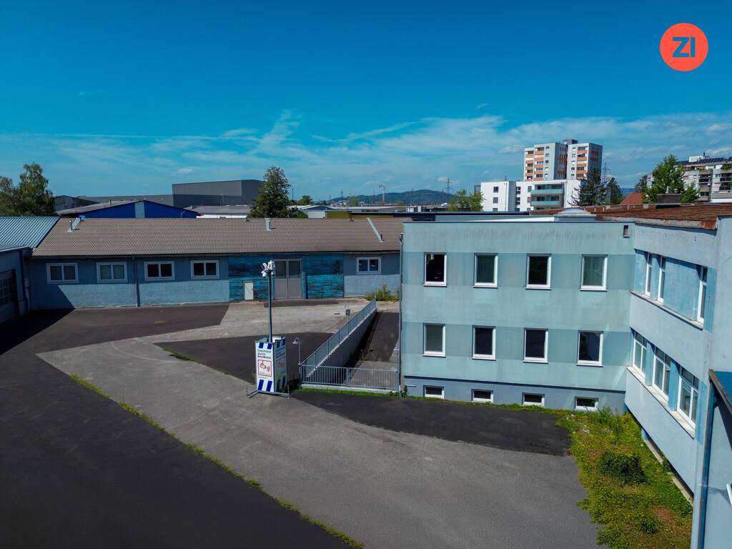 Gewerbegebäude mit einer Zufahrtsrampe zu einem Untergeschoss und einem großen Parkplatz.