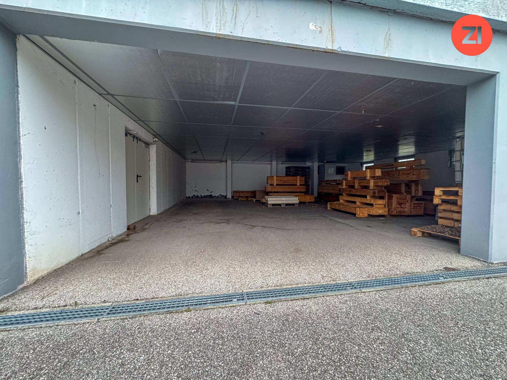 Geräumiger Lagerraum mit Betonboden und gestapelten Holzpaletten im hinteren Bereich.