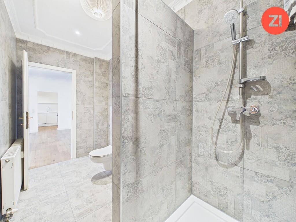 Duschbereich im modernen Badezimmer mit grauen Fliesen und hochwertiger Duscharmatur.