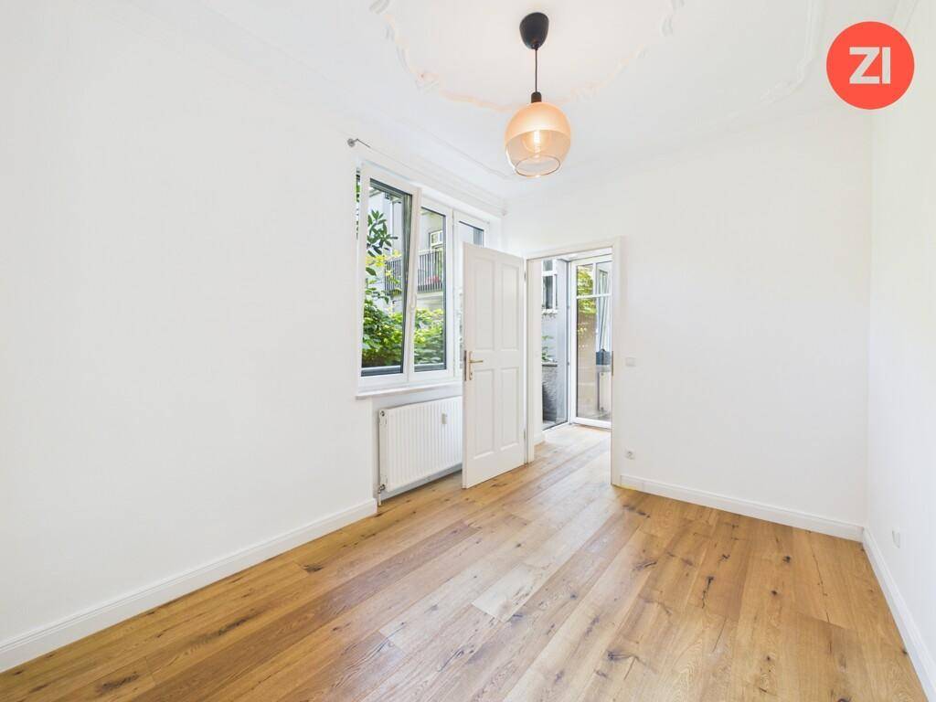 Geräumiges Zimmer mit Holzboden, hohen Decken und direktem Zugang zu einem Außenbereich.