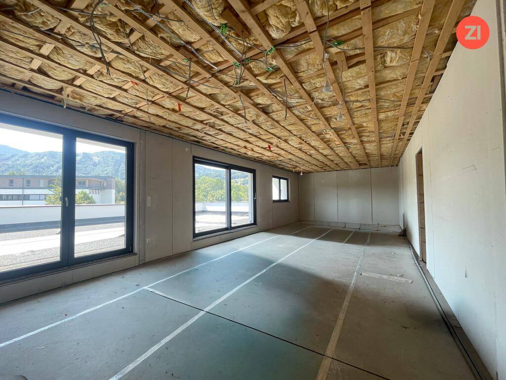 Unfertiger Innenraum mit sichtbarer Deckenisolierung und großen Schiebetüren, bereit für den Ausbau.