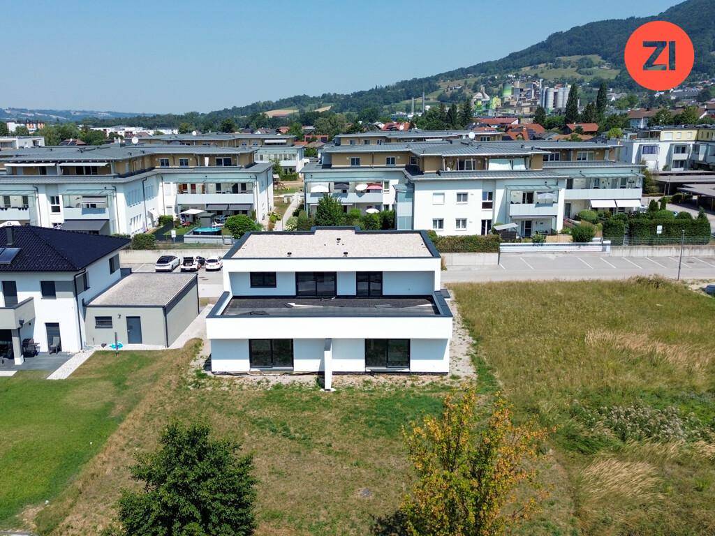 Luftaufnahme eines modernen weißen Gebäudes in einer Wohnsiedlung mit viel Grün.