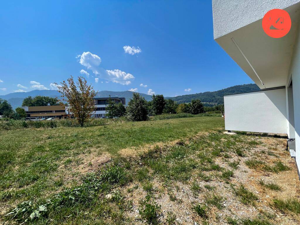 Weitläufiges Grundstück mit grüner Wiese und Blick auf die Berge.