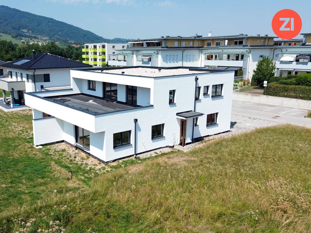 Moderne Doppelhaushälfte mit Flachdach und umliegender Bebauung in sonniger Lage.