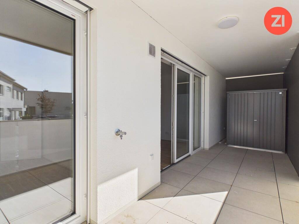 Überdachte Terrasse mit Fliesenboden und einem praktischen Abstellraum, ideal für entspannte Stunden.