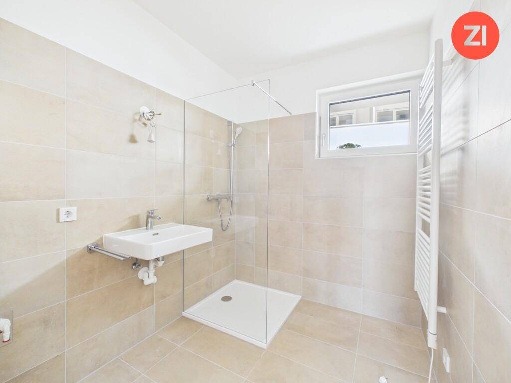 Modernes Badezimmer mit beigefarbenen Fliesen, einer ebenerdigen Dusche und einem Fenster.