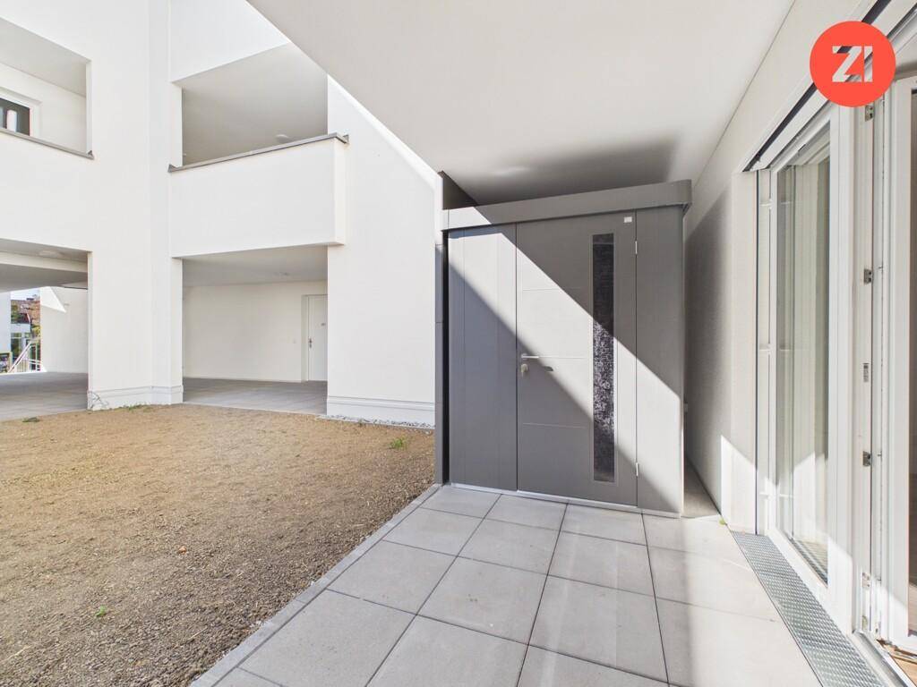 Außenbereich mit gepflasterter Terrasse, Abstellbox und Zugang zur Wohnung.