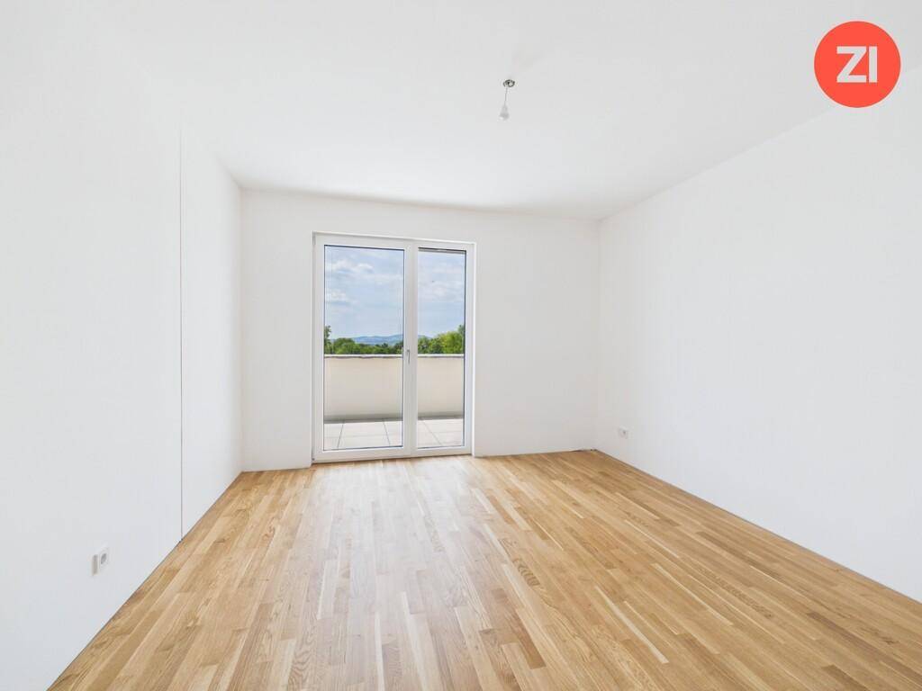 Helles Zimmer mit Parkettboden und großer Balkontür, bietet einen weiten Ausblick.