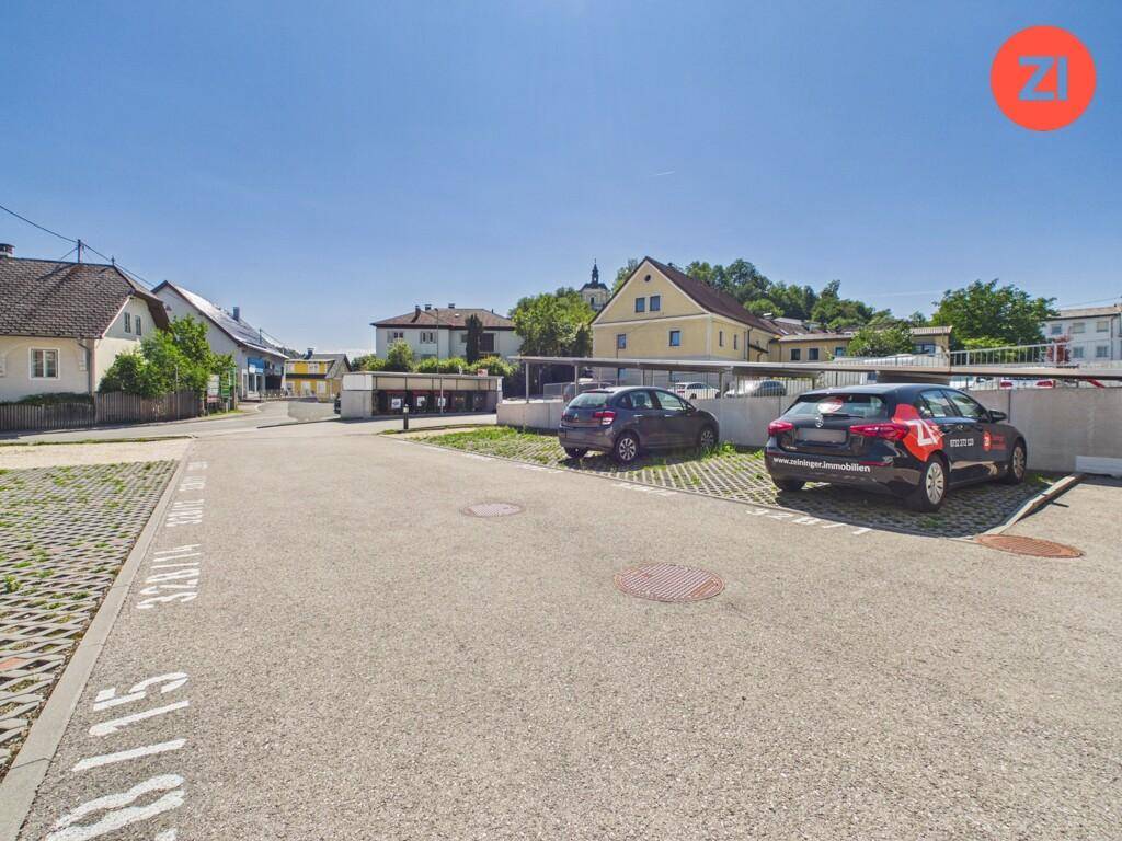 Außenparkplätze mit gepflastertem Bereich und Blick auf die umliegende Wohnsiedlung.