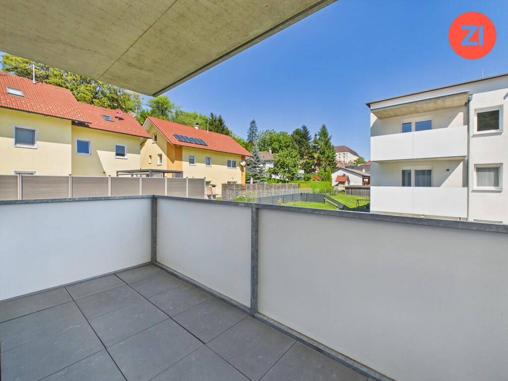Geräumiger Balkon mit Fliesenboden und weitem Blick auf die Wohngegend und Natur.