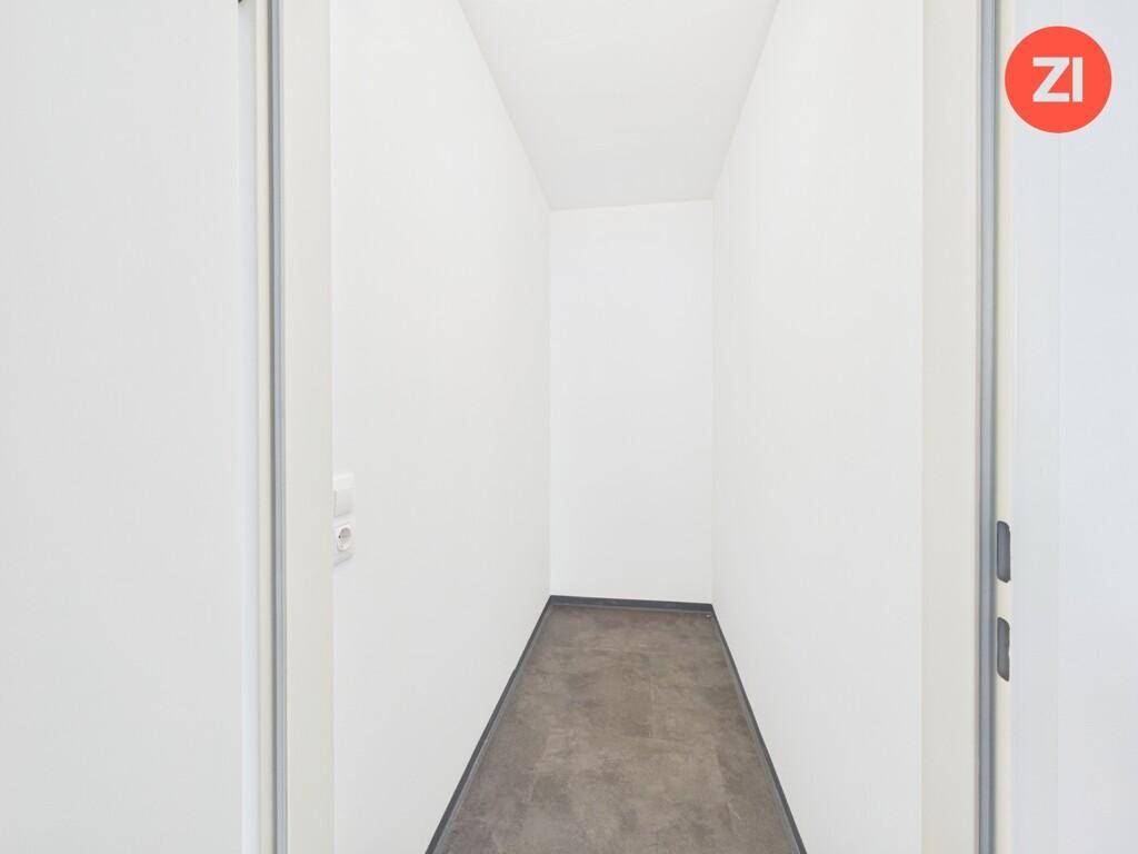 Kleiner, leerer Abstellraum mit dunklem Fliesenboden und weißen Wänden.