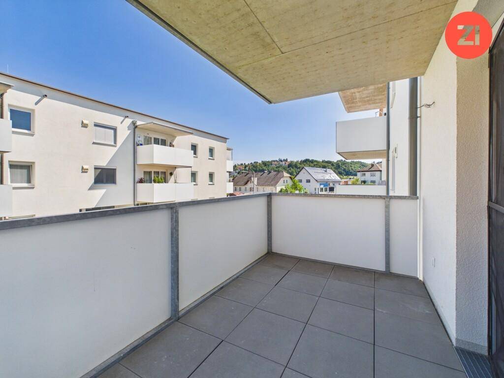 Moderner Balkon mit Fliesenboden und Blick auf die umliegenden Gebäude und Landschaft.