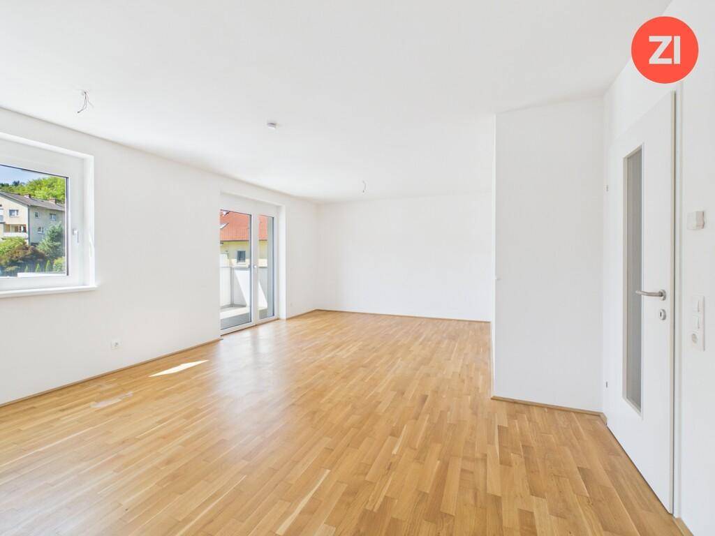 Geräumiges, helles Wohnzimmer mit Parkettboden und Zugang zu einem Balkon.