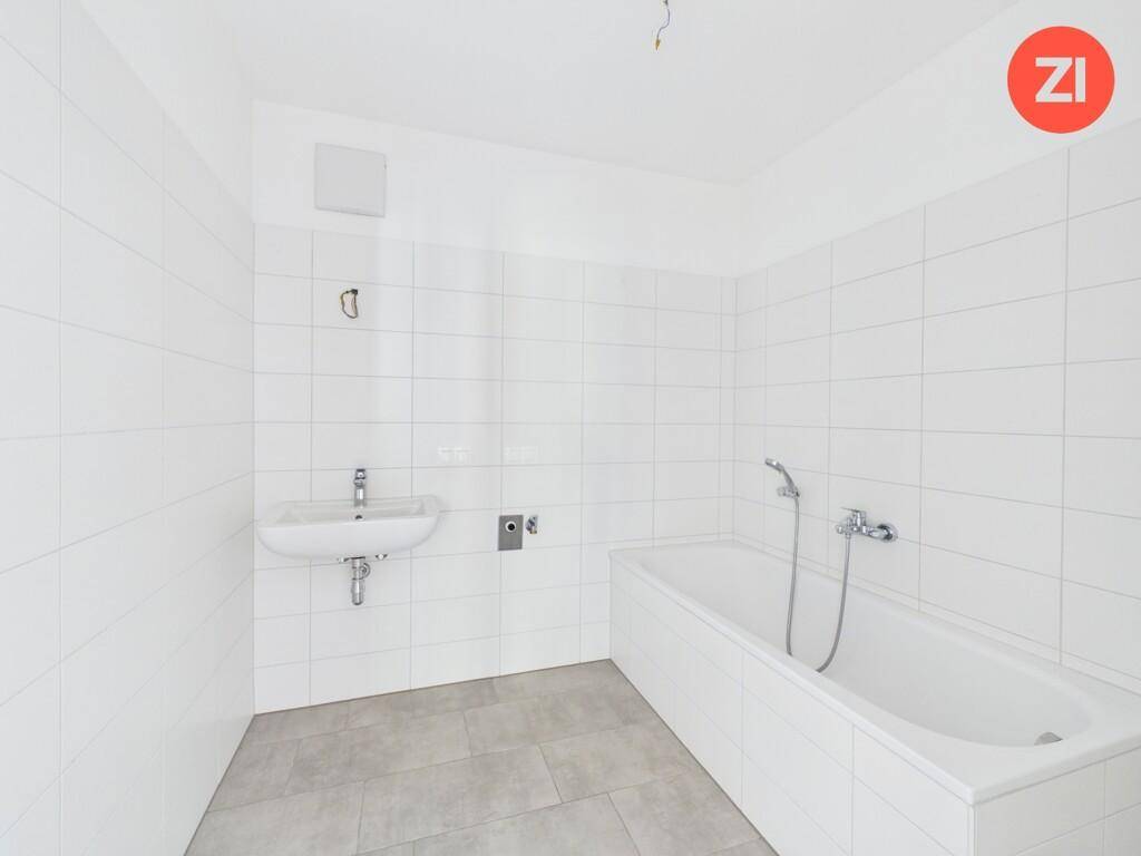 Modernes Badezimmer mit weißen Fliesen, Badewanne und Waschbecken.